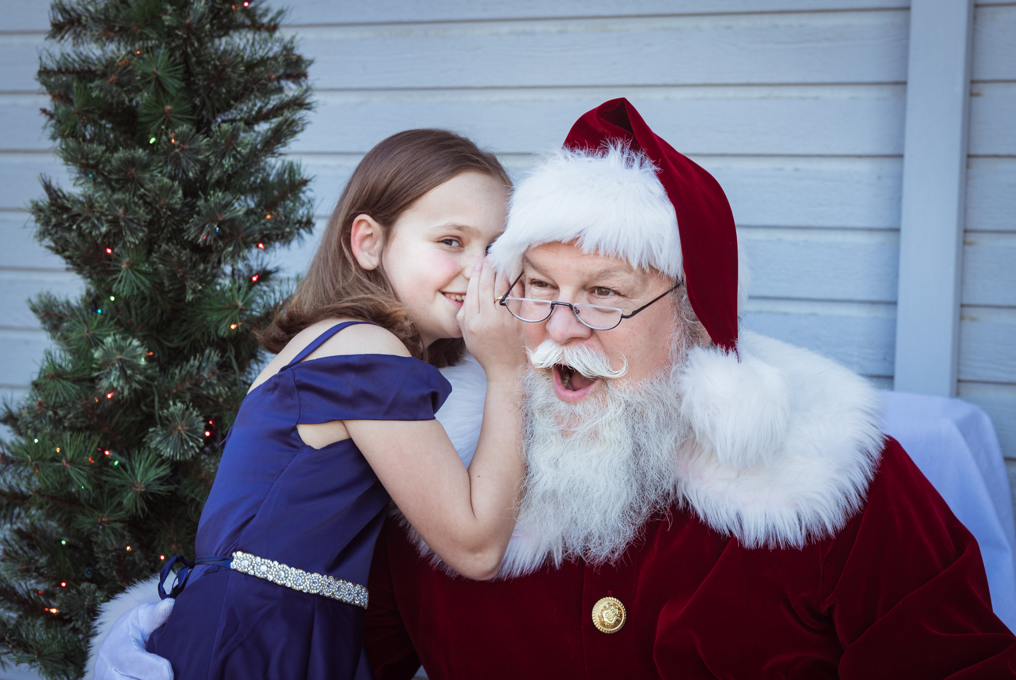 Young girl whispers her Christmas Wish List to Santa Dale