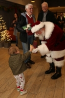 Young child offers Santa Dale a baby bottle. Milk for his cookies?